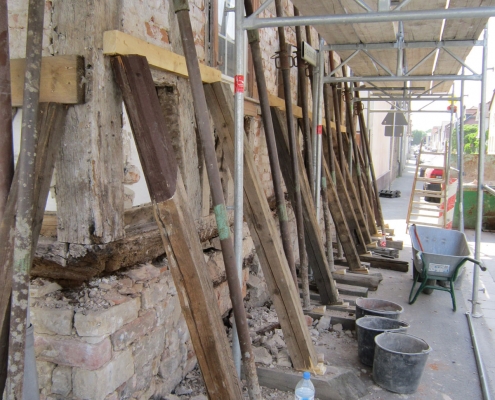 die Mauern eines Fachwerkhaues, das gerade restauriert wird, sind mit Holzbalken abgestützt