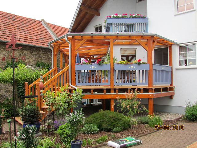 runde Holzveranda mit Treppenaufgang in lasiertem Holz mit blauem Geländer